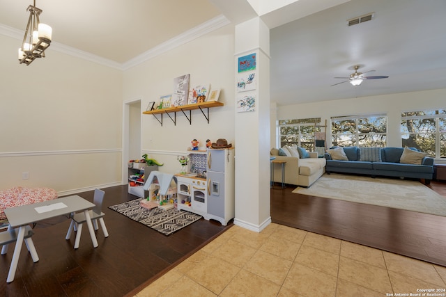 interior space with light wood-type flooring, ceiling fan with notable chandelier, and ornamental molding