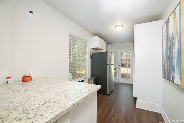 kitchen featuring light stone counters, stainless steel refrigerator, dark wood-type flooring, and white cabinetry