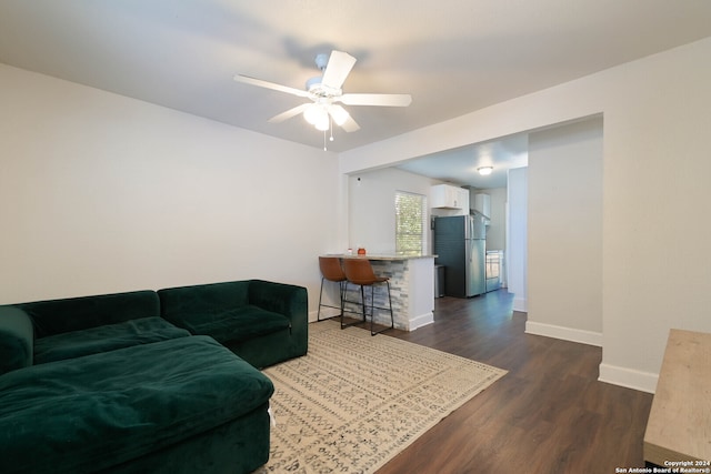 living room featuring ceiling fan and dark hardwood / wood-style flooring