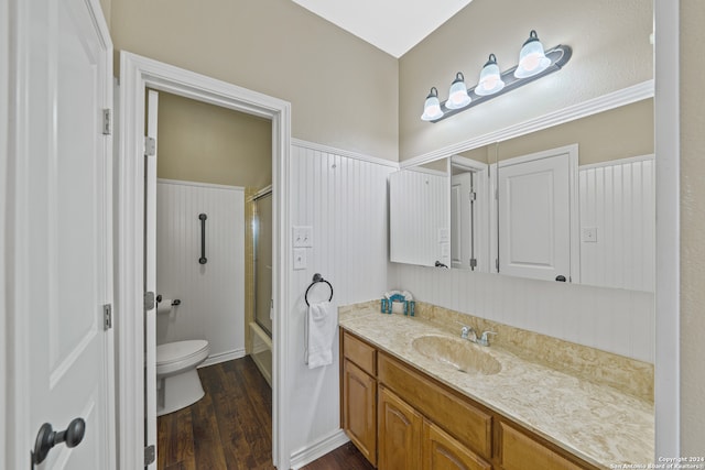 full bathroom featuring hardwood / wood-style floors, combined bath / shower with glass door, vanity, and toilet