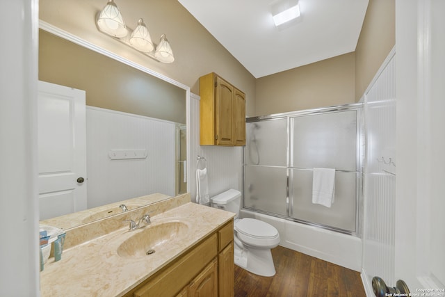 full bathroom featuring wood-type flooring, enclosed tub / shower combo, vanity, and toilet