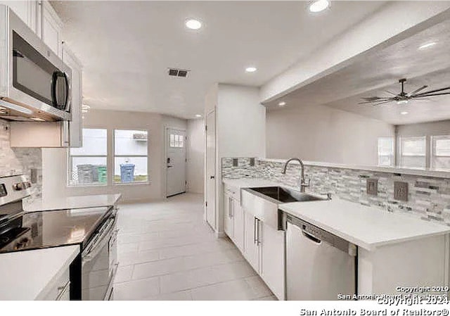 kitchen featuring ceiling fan, white cabinets, sink, tasteful backsplash, and appliances with stainless steel finishes