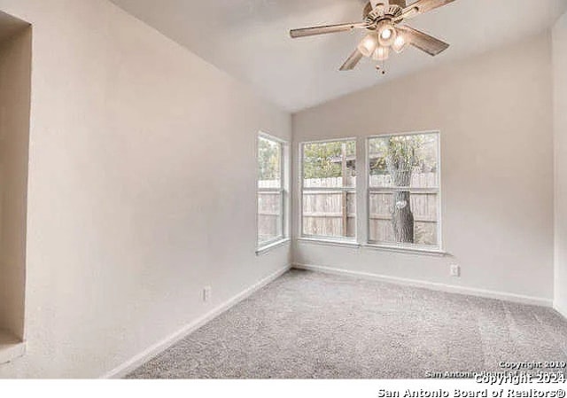 unfurnished room featuring carpet, vaulted ceiling, and ceiling fan