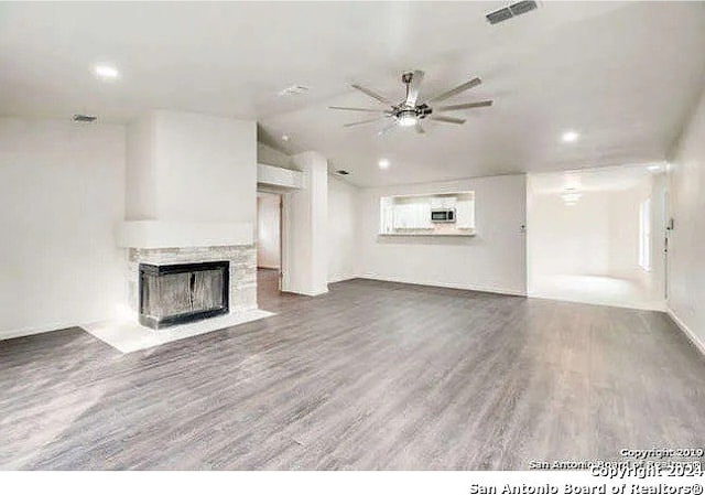 unfurnished living room with wood-type flooring, vaulted ceiling, and ceiling fan