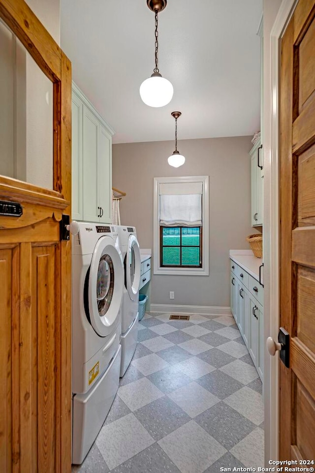 washroom with washing machine and clothes dryer and cabinets