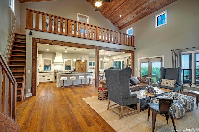 living room with french doors, high vaulted ceiling, wooden ceiling, an inviting chandelier, and light wood-type flooring