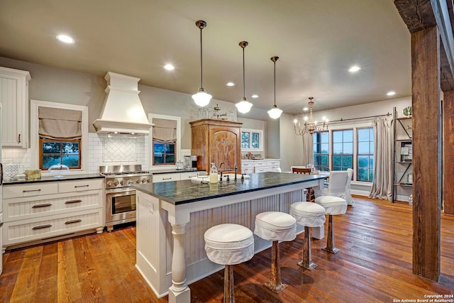 kitchen featuring wood-type flooring, a center island, custom range hood, a breakfast bar, and stainless steel range