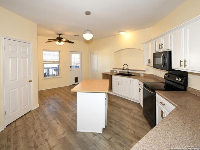 kitchen featuring sink, black appliances, pendant lighting, white cabinets, and a kitchen island