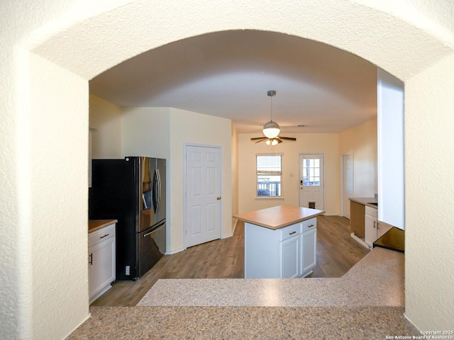 kitchen featuring a center island, stainless steel refrigerator with ice dispenser, ceiling fan, light hardwood / wood-style floors, and white cabinetry