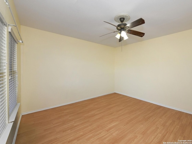 empty room with ceiling fan and light hardwood / wood-style flooring