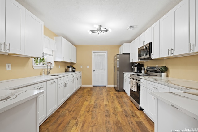 kitchen featuring dark wood-type flooring, light stone countertops, white cabinets, and stainless steel appliances