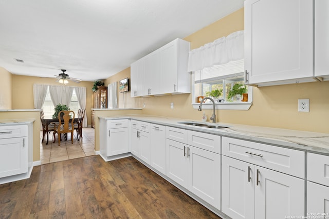 kitchen featuring dark hardwood / wood-style flooring, white cabinets, sink, ceiling fan, and light stone countertops