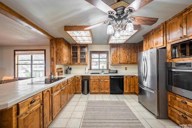 355 Mountain Creek Rd, Pipe Creek, TX 78063 - kitchen with black appliances, ceiling fan, brown cabinets, a sink, and light tile patterned flooring