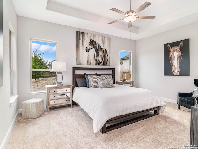 bedroom featuring ensuite bathroom, light colored carpet, visible vents, and a raised ceiling