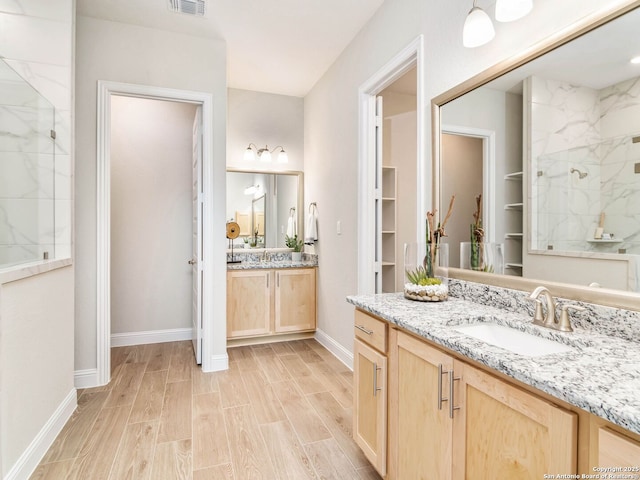 bathroom with vanity, a marble finish shower, recessed lighting, baseboards, and wood tiled floor