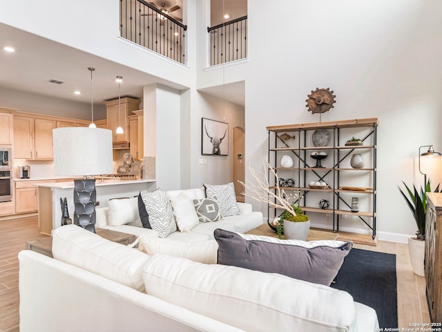 living area featuring a high ceiling, ceiling fan, light wood-style flooring, and recessed lighting