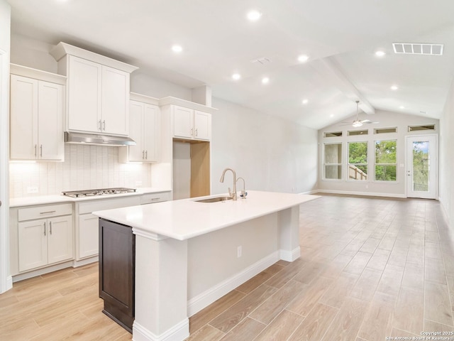 kitchen featuring stainless steel gas cooktop, a sink, open floor plan, under cabinet range hood, and visible vents