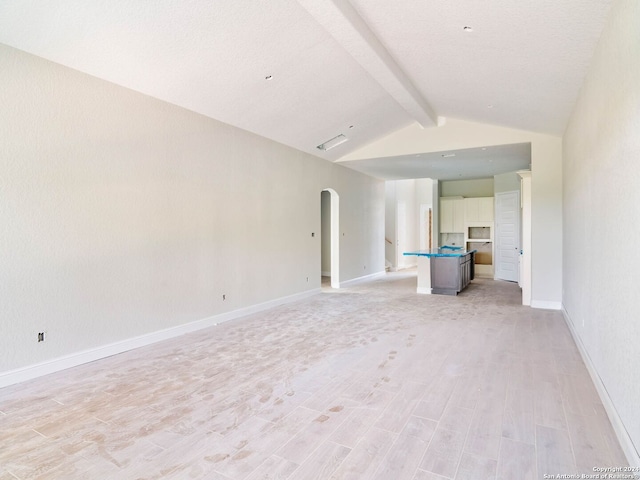 unfurnished living room with lofted ceiling with beams and light hardwood / wood-style floors