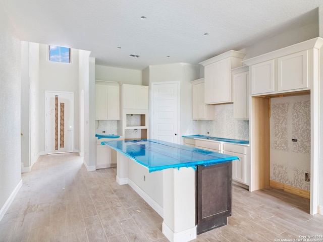 kitchen with light wood-type flooring, white cabinetry, and a center island