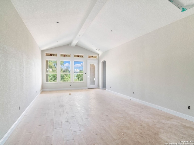 spare room with vaulted ceiling with beams and light wood-type flooring