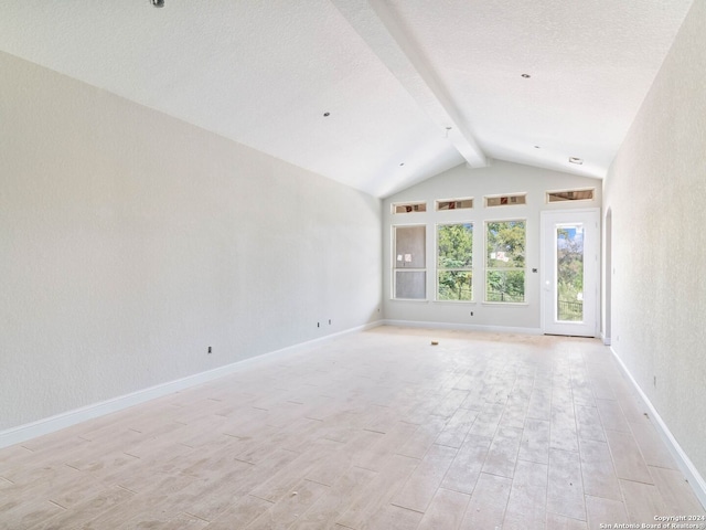 unfurnished room with vaulted ceiling with beams and light hardwood / wood-style flooring