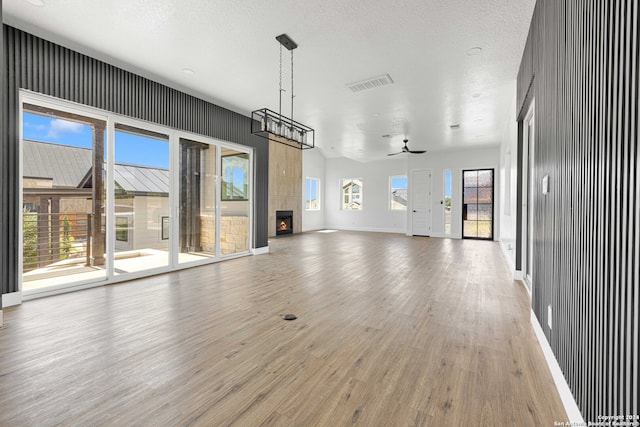 unfurnished living room featuring a healthy amount of sunlight, ceiling fan, and a fireplace