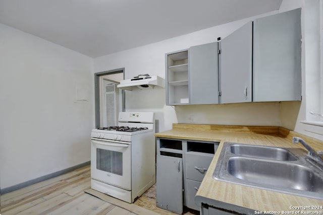 kitchen with gray cabinets, light hardwood / wood-style floors, sink, exhaust hood, and white range with gas stovetop