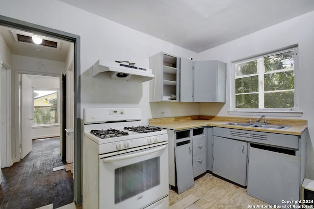 kitchen with gray cabinetry, a wealth of natural light, and gas range gas stove