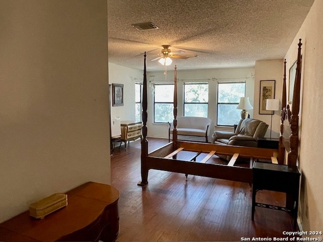 living room featuring ceiling fan, a textured ceiling, visible vents, and wood finished floors