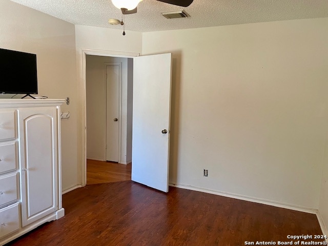 unfurnished bedroom featuring dark wood-style floors, ceiling fan, a textured ceiling, and visible vents