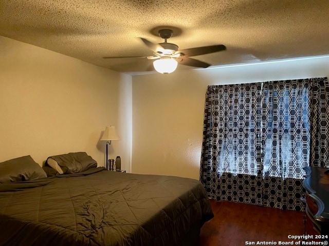 bedroom with ceiling fan, a textured ceiling, and wood finished floors