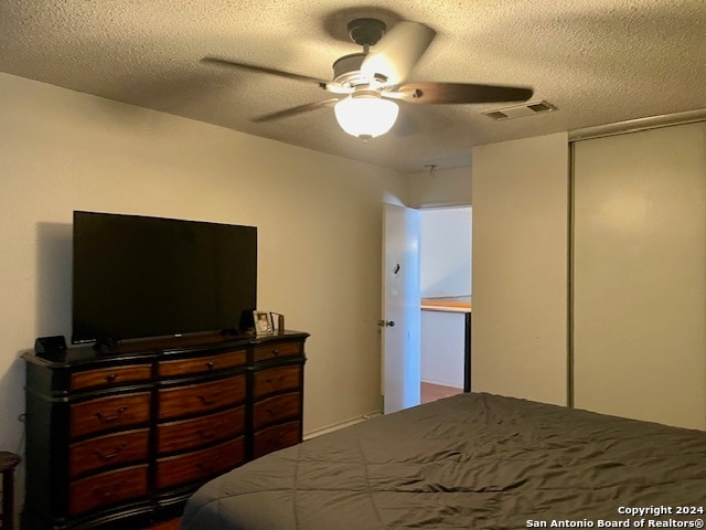 bedroom with a ceiling fan, a closet, visible vents, and a textured ceiling