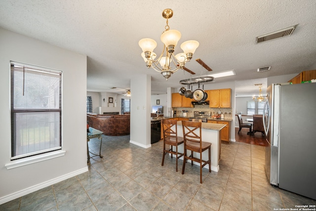 dining room featuring light tile patterned floors, visible vents, ceiling fan with notable chandelier, and a textured ceiling
