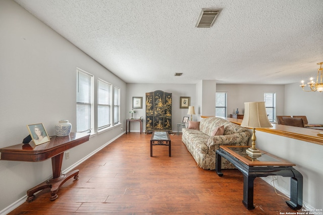 living room featuring a wealth of natural light, a notable chandelier, visible vents, and wood finished floors
