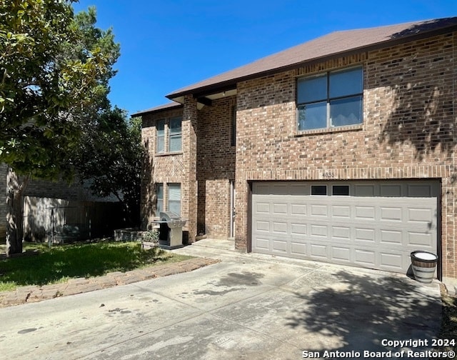 townhome / multi-family property featuring a garage, brick siding, and driveway