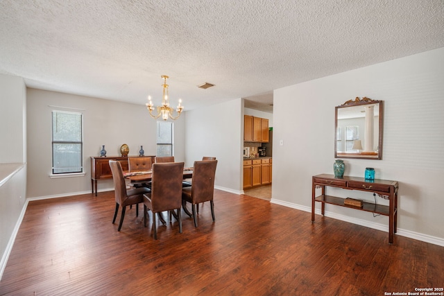 dining space with baseboards, plenty of natural light, an inviting chandelier, and wood finished floors