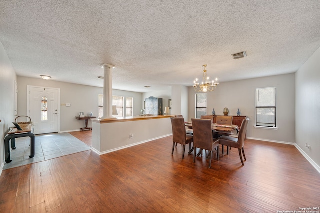 dining area featuring decorative columns, a wealth of natural light, visible vents, and dark wood-style floors