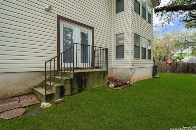 property entrance with a yard, fence, and central AC unit