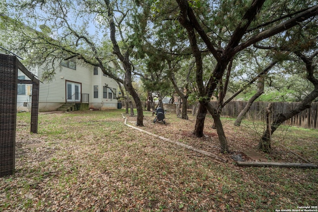 view of yard featuring entry steps, fence, and french doors