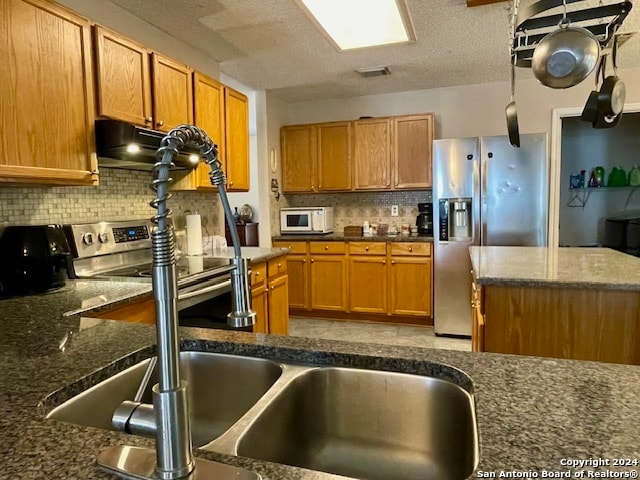 kitchen with stainless steel appliances, visible vents, decorative backsplash, a textured ceiling, and under cabinet range hood