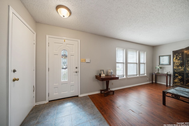 entryway with a textured ceiling, wood finished floors, and baseboards