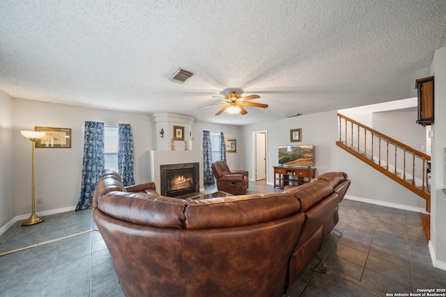living area with a fireplace, stairway, a textured ceiling, visible vents, and ceiling fan