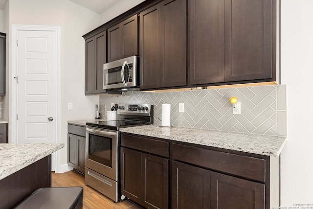 kitchen featuring dark brown cabinetry, light stone counters, tasteful backsplash, light hardwood / wood-style flooring, and stainless steel appliances