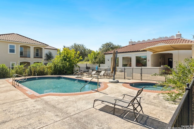 view of swimming pool featuring a hot tub and a patio area