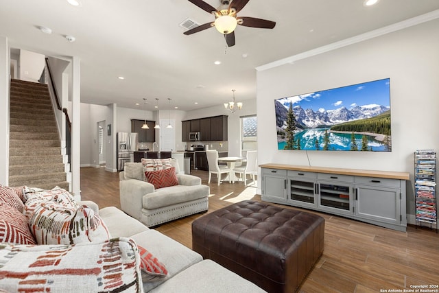 living room featuring ceiling fan with notable chandelier, hardwood / wood-style flooring, and ornamental molding