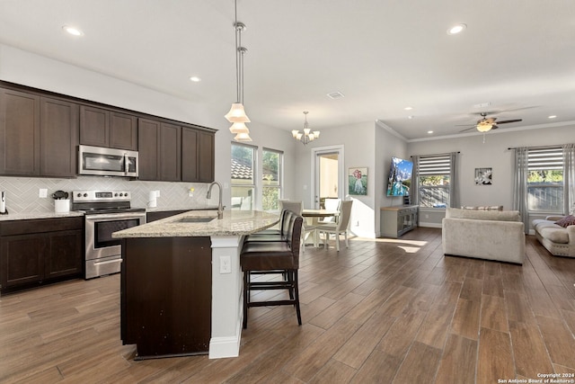 kitchen featuring an island with sink, stainless steel appliances, dark hardwood / wood-style floors, and plenty of natural light