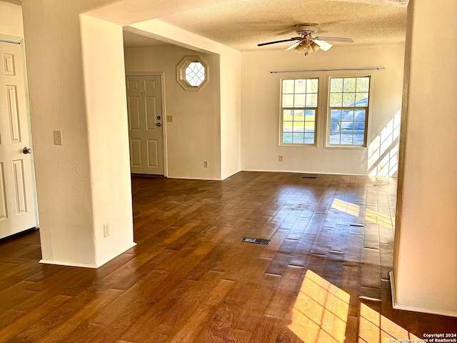 unfurnished room with a textured ceiling, ceiling fan, and dark hardwood / wood-style flooring