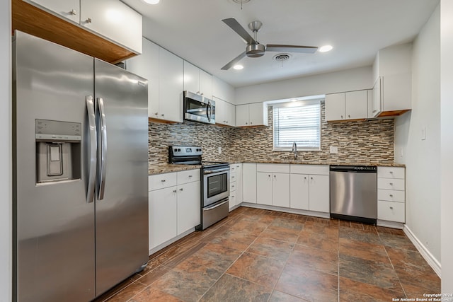 kitchen featuring ceiling fan, white cabinets, appliances with stainless steel finishes, dark stone counters, and decorative backsplash