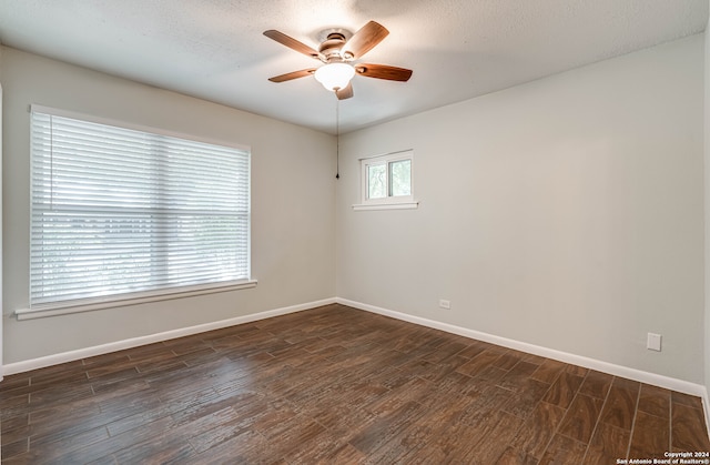 empty room with ceiling fan, dark wood-type flooring, and a textured ceiling