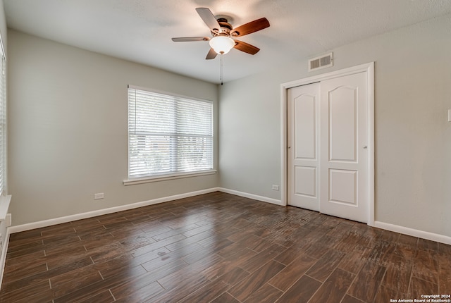 unfurnished bedroom featuring ceiling fan, a closet, and dark wood-type flooring